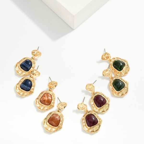 Hammered Frame Stone Drop Earrings with organic, textured settings surrounding a glossy marbled stone. The irregular shapes give them an artisan, vintage inspired feel that pairs well with fall knits and holiday dresses. Post backs keep them comfortable and secure. Bold yet wearable, these statement earrings are an easy upsell for customers shopping for something special.