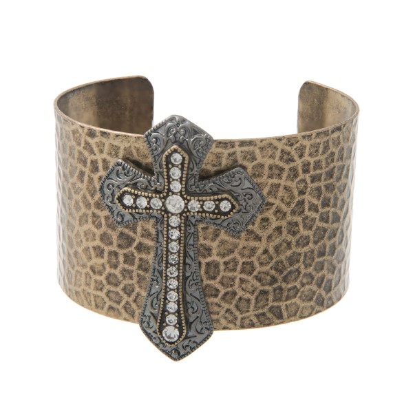 Burnished gold tone cuff bracelet displaying a hematite tone cross with rhinestones.