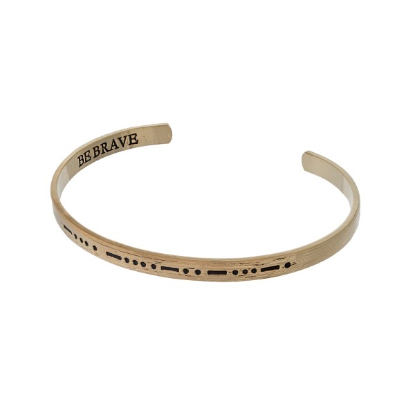 Gold tone cuff bracelet stamped on the outside with morse code and "be brave' on the inside. 