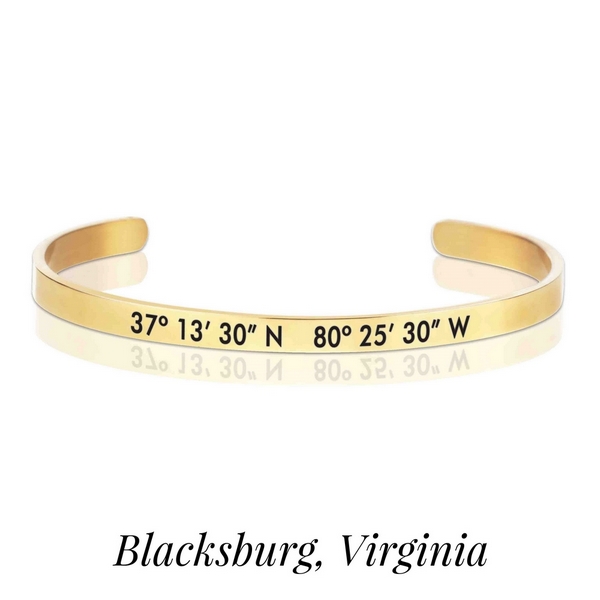 Gold tone cuff bracelet stamped with the coordinates of Blacksburg, Virginia. 