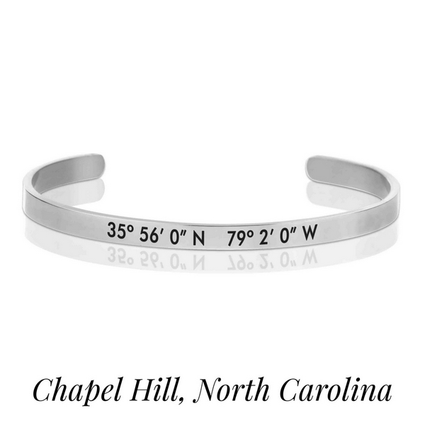 Silver tone cuff bracelet stamped with the coordinates of Chapel Hill, North Carolina. 