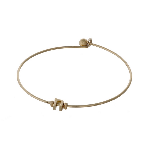 Dainty gold tone bangle bracelet with a lowercase "N" initial. 