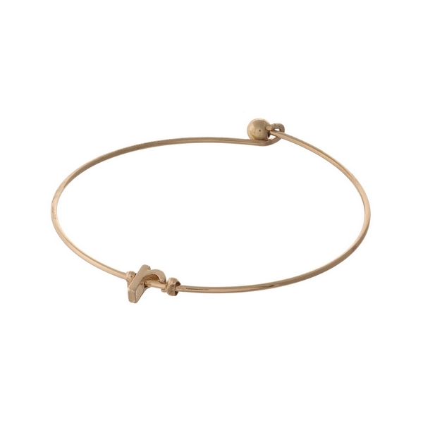 Dainty gold tone bangle bracelet with a lowercase "R" initial.