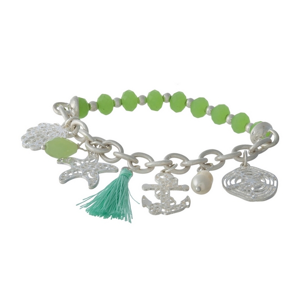 Silver tone and green beaded stretch bracelet displaying sealife and tassel charms. 