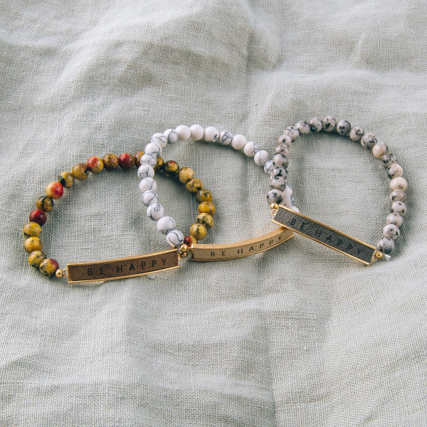 Natural stone beaded stretch bracelet featuring a faux leather focal with "Be Happy" engraved details. Approximately 3" in diameter unstretched. Fits up to a 6" wrist.