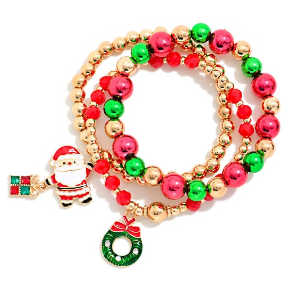 Christmas Charm Stretch Bracelet Set of three, featuring polished metallic beads, faceted crystal beads, and festive enamel charms of Santa with a gift box and a holiday wreath. Each bracelet slips on easily with a comfortable stretch fit, and the trio looks best stacked together for a full, jolly arm party. Perfect for holiday parties, ugly sweater days, teacher gifts, and stocking stuffers. A fun seasonal impulse buy that flies off counter displays from Thanksgiving to New Year's.
