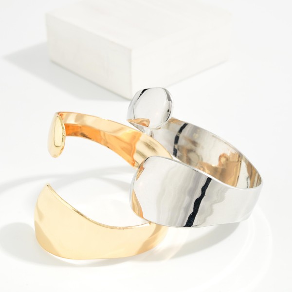 Sculpted Wrap Cuff Bracelet with a wide, high polish band that tapers and overlaps for a fluid, modern silhouette. The open cuff design slides on easily and adjusts gently for a comfortable fit. Wear it alone as a statement or stack it with bangles and watches. Bold, minimalist metal cuffs are a strong trend and an easy, giftable seller at boutique price points.