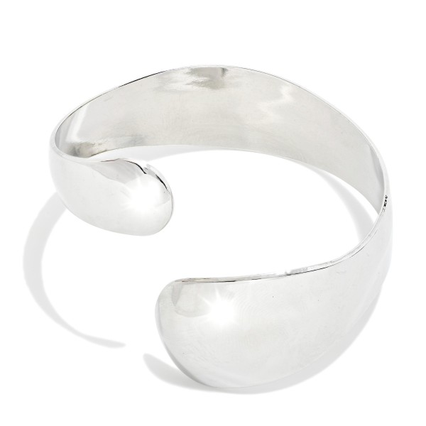 Sculpted Wrap Cuff Bracelet with a wide, high polish band that tapers and overlaps for a fluid, modern silhouette. The open cuff design slides on easily and adjusts gently for a comfortable fit. Wear it alone as a statement or stack it with bangles and watches. Bold, minimalist metal cuffs are a strong trend and an easy, giftable seller at boutique price points.