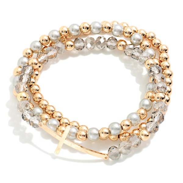 Sideways Cross Beaded Bracelet Set featuring coordinated strands of faceted glass beads, faux pearls, and polished metal beads, anchored by an east west cross centerpiece. Wear the full stack for impact or split the strands for a lighter look. Stretch fit for easy on and off. A popular faith style offered in several bead mixes, it's an easy gift for any occasion.