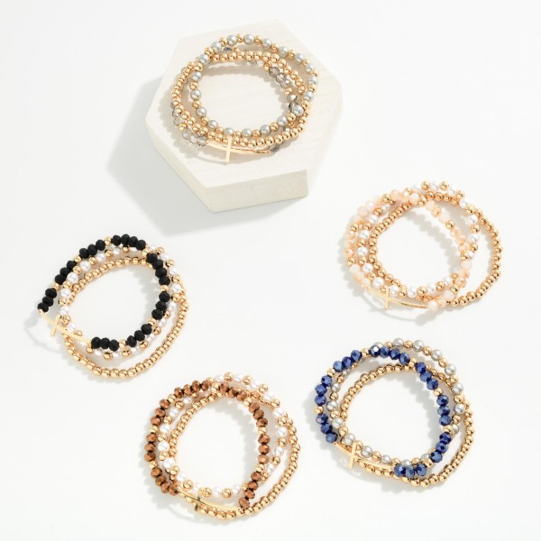 Sideways Cross Beaded Bracelet Set featuring coordinated strands of faceted glass beads, faux pearls, and polished metal beads, anchored by an east west cross centerpiece. Wear the full stack for impact or split the strands for a lighter look. Stretch fit for easy on and off. A popular faith style offered in several bead mixes, it's an easy gift for any occasion.