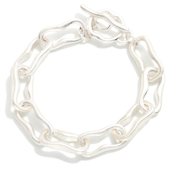 Organic Link Toggle Bracelet featuring wavy, molten style oval links in a soft brushed finish with a front toggle closure. The irregular shapes give it an artisan feel that stands out from classic chains. Easy to fasten and comfortable for all day wear. A modern chain bracelet that stacks well with bangles and pairs with both casual and dressy outfits.