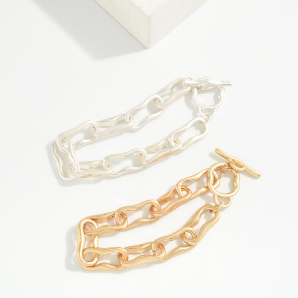 Organic Link Toggle Bracelet featuring wavy, molten style oval links in a soft brushed finish with a front toggle closure. The irregular shapes give it an artisan feel that stands out from classic chains. Easy to fasten and comfortable for all day wear. A modern chain bracelet that stacks well with bangles and pairs with both casual and dressy outfits.