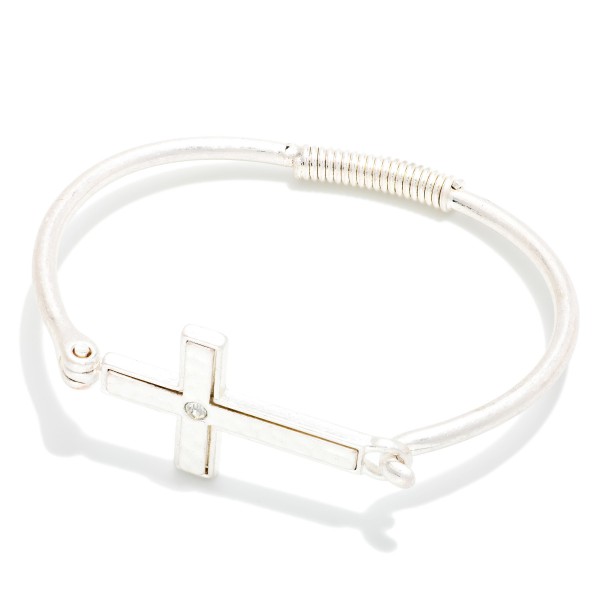 Sideways Cross Wire Bangle Bracelet featuring a polished east west cross centered on a slim wire band with a coiled wrap detail. The hook closure makes it easy to put on and take off. A subtle, meaningful faith piece that stacks beautifully with other bangles. An affordable gift for baptisms, confirmations, and Easter, and a reliable everyday seller.