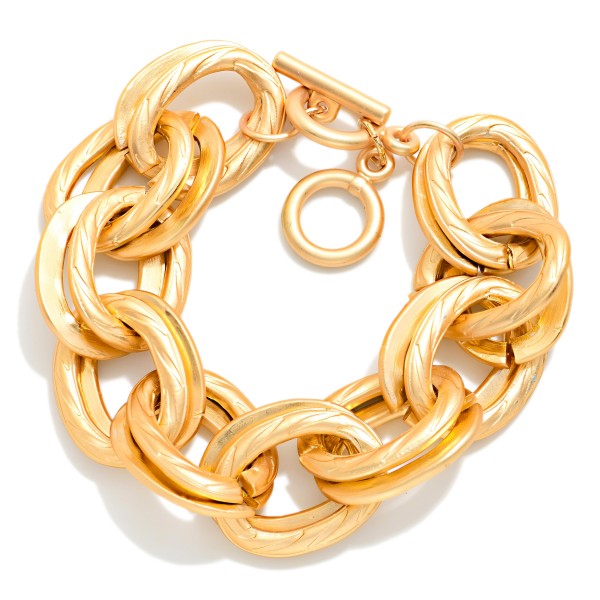 Chunky Chain Link Toggle Bracelet featuring oversized oval links in a soft matte finish and a front toggle closure. Lightweight for its size, it delivers a bold look without weighing down the wrist. Pairs perfectly with the coordinating chunky chain necklace for a complete set. A trend favorite at an easy price point that sells quickly in boutiques.