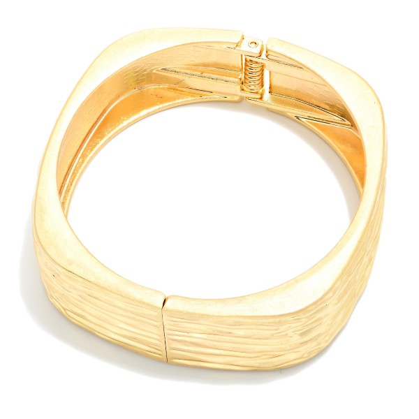 Ridged Square Hinged Bangle Bracelet with a soft cornered shape and a textured ribbed finish. The modern silhouette offers a fresh alternative to classic round bangles. Hinged for easy on and off with a secure closure. A sleek, architectural statement piece that pairs with workwear and weekend outfits alike, perfect for customers looking for something different.