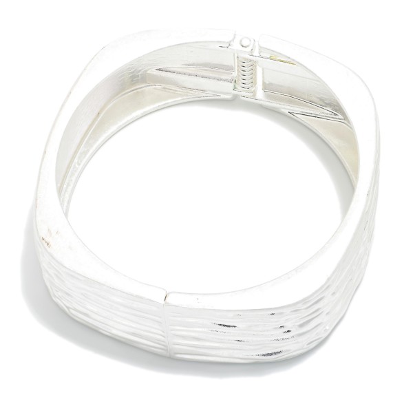 Ridged Square Hinged Bangle Bracelet with a soft cornered shape and a textured ribbed finish. The modern silhouette offers a fresh alternative to classic round bangles. Hinged for easy on and off with a secure closure. A sleek, architectural statement piece that pairs with workwear and weekend outfits alike, perfect for customers looking for something different.