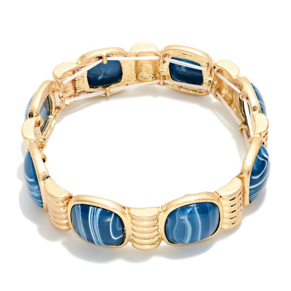 Marbled Stone Stretch Bracelet featuring cushion cut stones with a swirled, glossy finish set between ribbed metal spacers. The stretch fit slides on easily and sits comfortably on most wrists. The bold stones give it a vintage inspired, statement look that pairs well with knits and holiday dresses. Offered in several stone options, it's an easy seller for stacking and coordinating displays.