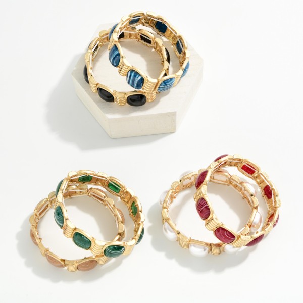 Marbled Stone Stretch Bracelet featuring cushion cut stones with a swirled, glossy finish set between ribbed metal spacers. The stretch fit slides on easily and sits comfortably on most wrists. The bold stones give it a vintage inspired, statement look that pairs well with knits and holiday dresses. Offered in several stone options, it's an easy seller for stacking and coordinating displays.