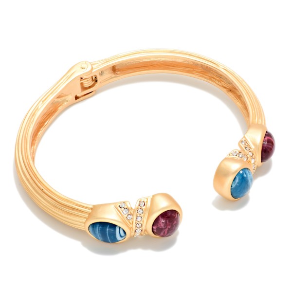 Stone Tip Open Cuff Bracelet featuring a ribbed matte band with round cabochon stones at each end and sparkling rhinestone accents. The open cuff design slips on easily and adjusts to most wrists. Bold enough to wear alone yet easy to stack with bangles and watches. A polished statement cuff that makes a great holiday gift and an easy upsell for customers shopping your bracelet display.