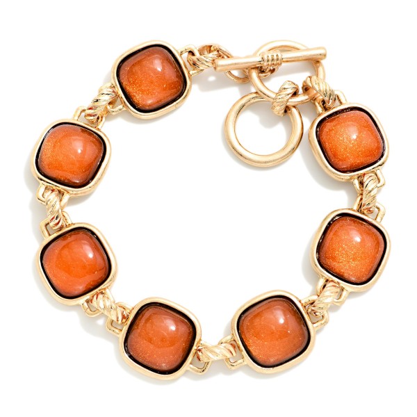 Square Stone Station Toggle Bracelet featuring glossy cushion cut cabochon stones in framed bezels linked together and finished with a front toggle closure. The vintage inspired design pairs perfectly with the coordinating square stone necklaces and earrings for a complete look. Comfortable and easy to fasten. A polished, giftable bracelet that adds instant interest to sweaters and holiday outfits.