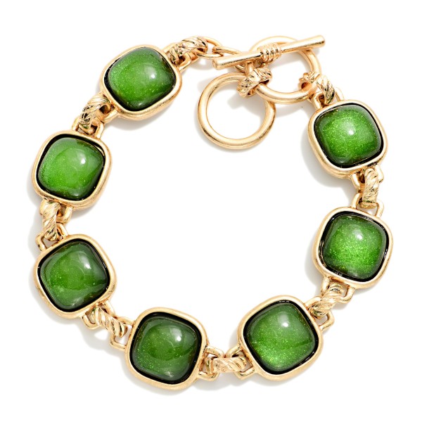 Square Stone Station Toggle Bracelet featuring glossy cushion cut cabochon stones in framed bezels linked together and finished with a front toggle closure. The vintage inspired design pairs perfectly with the coordinating square stone necklaces and earrings for a complete look. Comfortable and easy to fasten. A polished, giftable bracelet that adds instant interest to sweaters and holiday outfits.