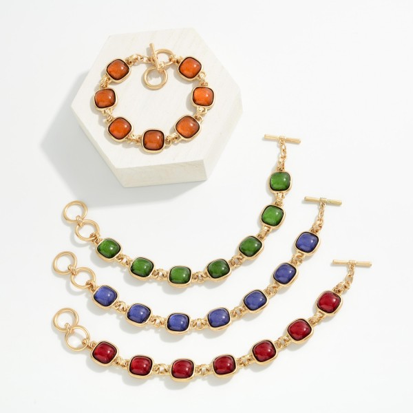Square Stone Station Toggle Bracelet featuring glossy cushion cut cabochon stones in framed bezels linked together and finished with a front toggle closure. The vintage inspired design pairs perfectly with the coordinating square stone necklaces and earrings for a complete look. Comfortable and easy to fasten. A polished, giftable bracelet that adds instant interest to sweaters and holiday outfits.