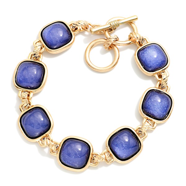 Square Stone Station Toggle Bracelet featuring glossy cushion cut cabochon stones in framed bezels linked together and finished with a front toggle closure. The vintage inspired design pairs perfectly with the coordinating square stone necklaces and earrings for a complete look. Comfortable and easy to fasten. A polished, giftable bracelet that adds instant interest to sweaters and holiday outfits.
