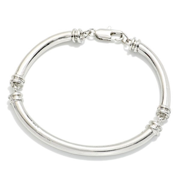 Polished Tube Hinged Bangle Bracelet with a smooth, rounded profile and ribbed accents at the hinge. The hinged design opens wide for easy on and off and closes securely. A clean, classic bangle that stacks well with watches, beaded stretch bracelets, and charm styles. Timeless and versatile, it's an easy everyday seller for customers of all ages.