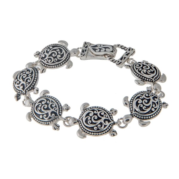 7 1/2" around silver tone charm bracelet featuring swimming sea turtles in a filigree design.