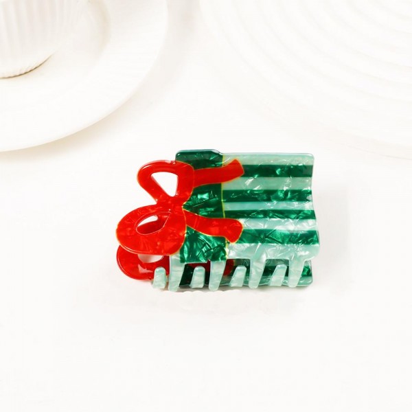 Holiday-shaped claw hair clip molded in glossy acrylic with hand-painted seasonal detail and a glitter-flecked finish. Strong-grip teeth hold a twist, a half-up, or a full clip-up on fine and thick hair alike, so it works for everyday wear and not just the party. A natural stocking stuffer, teacher gift, and secret-santa filler that buyers grab in multiples. Small footprint and low price point make it an easy counter or holiday-display add.