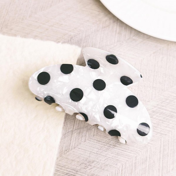 Polka dot claw hair clip in smooth acrylic with contrast painted dots and a mid-size profile. Strong-grip teeth hold a twist, a half-up, or a full clip-up on fine and thick hair alike without pulling or sliding out. Polka dots are a perennial retro print that pairs just as easily with denim and knits as with workwear. A steady everyday seller at an impulse price, and an easy multiple for customers building a clip collection.