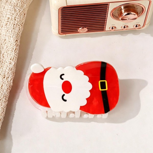 Santa claw clip molded in glossy acrylic with a painted belt detail and a friendly face across the front. The jaw holds a half up twist or clips back a fringe, and the character is recognizable at a glance on a peg display. Light on the head and sturdy in the hand. Holiday character clips are one of the easiest add on sales in December.