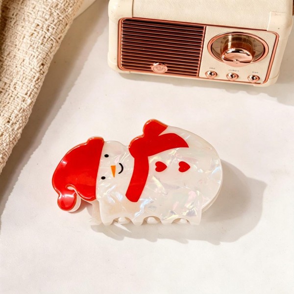 Snowman claw clip molded in glossy acrylic with a scarf detail and a cheerful painted face. The jaw grips a half up twist or holds a fringe back for photos, and the shape reads clearly from across a room. Light enough to wear through a full day of parties and dinners. Holiday character clips are an easy stocking stuffer and a strong register add on.