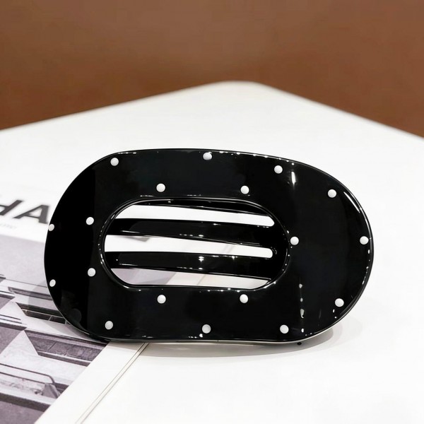 Oval hair barrette in a smooth acrylic finish with a scattered dot print and a hidden snap bar that clicks shut over a half up style or a low ponytail. The wide oval face covers the hardware, so the look stays clean from every angle. Comfortable enough to leave in through a full day at a desk. Statement barrettes finish a simple hairstyle in one step and sell steadily off a peg display.