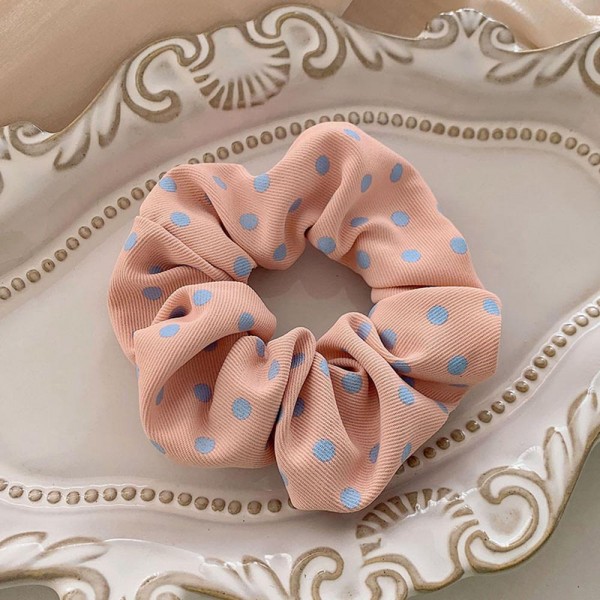 Polka dot scrunchie in a soft chiffon style fabric with a generous gathered body that grips without pulling. The wide covered elastic holds a ponytail or a bun securely and slides out without leaving a crease. A printed take on an everyday essential that customers collect and replace rather than buy once. Scrunchies at this price are the definition of an impulse add at the register.