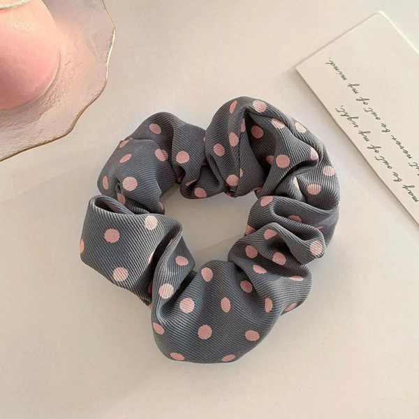 Polka dot scrunchie in a soft chiffon style fabric with a generous gathered body that grips without pulling. The wide covered elastic holds a ponytail or a bun securely and slides out without leaving a crease. A printed take on an everyday essential that customers collect and replace rather than buy once. Scrunchies at this price are the definition of an impulse add at the register.