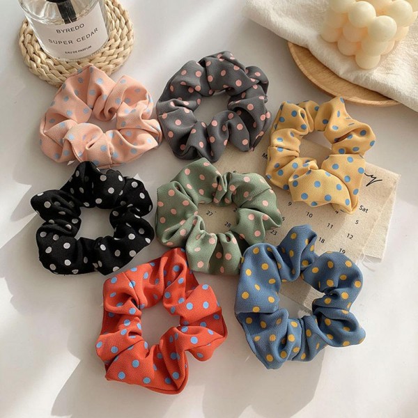 Polka dot scrunchie in a soft chiffon style fabric with a generous gathered body that grips without pulling. The wide covered elastic holds a ponytail or a bun securely and slides out without leaving a crease. A printed take on an everyday essential that customers collect and replace rather than buy once. Scrunchies at this price are the definition of an impulse add at the register.
