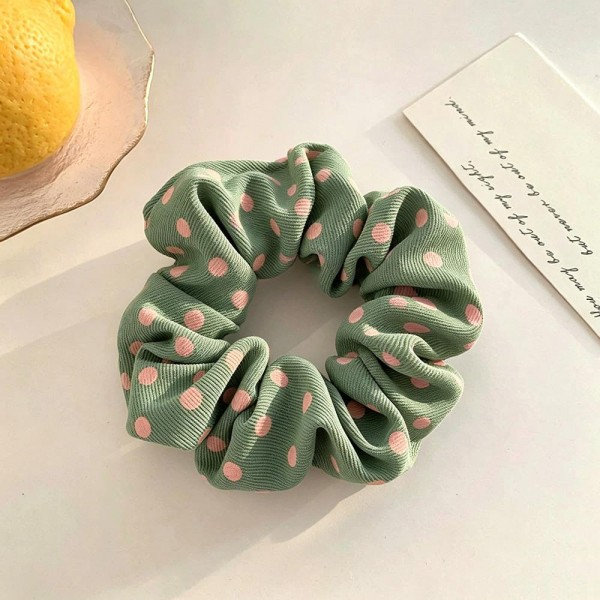 Polka dot scrunchie in a soft chiffon style fabric with a generous gathered body that grips without pulling. The wide covered elastic holds a ponytail or a bun securely and slides out without leaving a crease. A printed take on an everyday essential that customers collect and replace rather than buy once. Scrunchies at this price are the definition of an impulse add at the register.