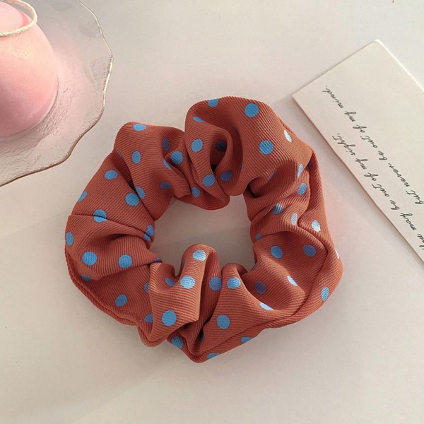 Polka dot scrunchie in a soft chiffon style fabric with a generous gathered body that grips without pulling. The wide covered elastic holds a ponytail or a bun securely and slides out without leaving a crease. A printed take on an everyday essential that customers collect and replace rather than buy once. Scrunchies at this price are the definition of an impulse add at the register.