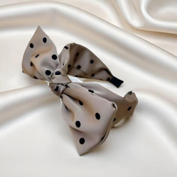 Oversized bow headband in a smooth satin finish, built on a padded band that sits comfortably behind the ears. The bow is stitched to hold its shape so it stays upright through a full day of wear. It dresses up a simple ponytail for weddings, holiday parties, and photo days, and looks just as good with jeans. Bow headbands are a proven impulse item that sells in multiples.