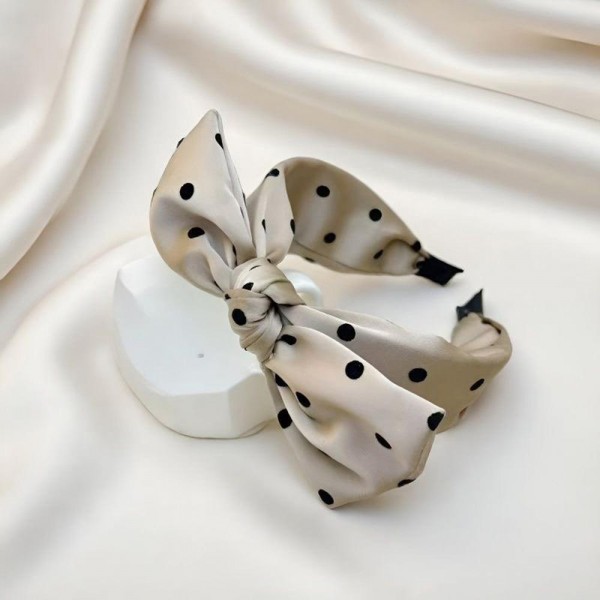 Oversized bow headband in a smooth satin finish, built on a padded band that sits comfortably behind the ears. The bow is stitched to hold its shape so it stays upright through a full day of wear. It dresses up a simple ponytail for weddings, holiday parties, and photo days, and looks just as good with jeans. Bow headbands are a proven impulse item that sells in multiples.