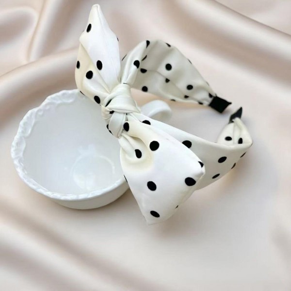 Oversized bow headband in a smooth satin finish, built on a padded band that sits comfortably behind the ears. The bow is stitched to hold its shape so it stays upright through a full day of wear. It dresses up a simple ponytail for weddings, holiday parties, and photo days, and looks just as good with jeans. Bow headbands are a proven impulse item that sells in multiples.