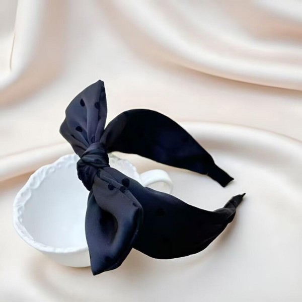 Oversized bow headband in a smooth satin finish, built on a padded band that sits comfortably behind the ears. The bow is stitched to hold its shape so it stays upright through a full day of wear. It dresses up a simple ponytail for weddings, holiday parties, and photo days, and looks just as good with jeans. Bow headbands are a proven impulse item that sells in multiples.