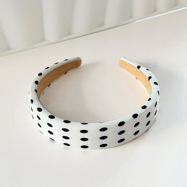 Padded headband with an allover polka dot print and a wide crown that holds hair back without pinching behind the ears. The firm band keeps its shape through a full day and the smooth finish will not snag fine hair. A retro print that dresses up a simple ponytail or a fresh blowout in one step. Headbands like this are a quick impulse add and they photograph beautifully on a display.