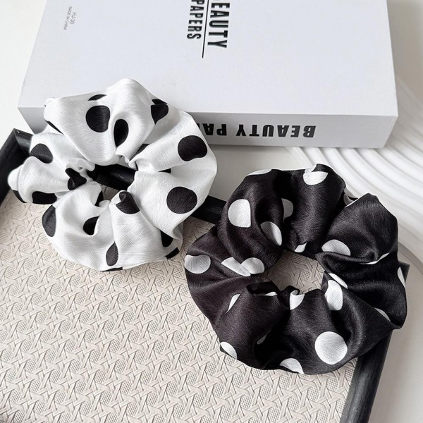 Polka Dot Satin Scrunchie with a smooth, silky finish and a soft elastic core that holds ponytails and buns without creasing or tugging. The full, gathered shape adds instant polish to a simple ponytail and doubles as a cute wrist accessory. Gentle on hair for everyday wear, workouts, and sleep. An easy, affordable add on that customers love to grab in every print.