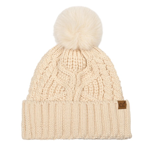 Cable Knit Pom Beanie with a bold braided cable running up the front and a tall ribbed cuff that folds over for a double layer of warmth. A plump faux fur pom finishes the top, and a small faux leather patch adds a polished touch at the cuff. Made for chilly game days, holiday shopping, and weekend getaways. Cable knit pom beanies are a proven winter best seller and an easy reorder for any boutique hat wall.