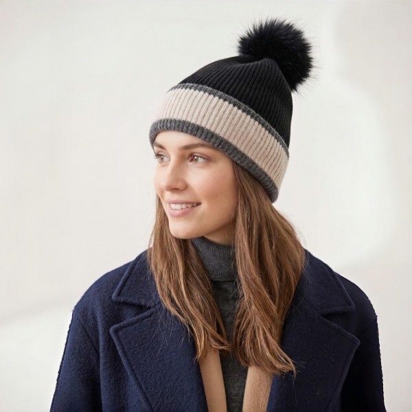 Chunky Knit Pom Beanie with contrast striped cuff and an oversized faux fur pom. The soft, stretchy ribbed knit keeps its shape while delivering cozy warmth on cold-weather days — an effortless topper for errands, game days, and après-ski style. A cold-season bestseller that sells through fast once temperatures drop; boutique customers grab these for themselves and as gifts.