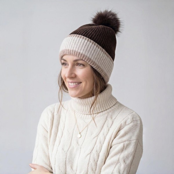 Chunky Knit Pom Beanie with contrast striped cuff and an oversized faux fur pom. The soft, stretchy ribbed knit keeps its shape while delivering cozy warmth on cold-weather days — an effortless topper for errands, game days, and après-ski style. A cold-season bestseller that sells through fast once temperatures drop; boutique customers grab these for themselves and as gifts.