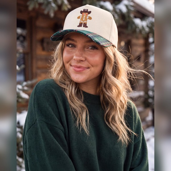 Gingerbread Cowboy Embroidered Baseball Cap featuring a smiling gingerbread man in a cowboy hat and boots stitched on the front panel. The structured crown is paired with a plaid brim and matching plaid top button for a festive, western inspired finish. Perfect for Christmas markets, holiday parties, and cozy winter outfits. A fun seasonal cap that makes an easy gift and sells fast through the holidays.