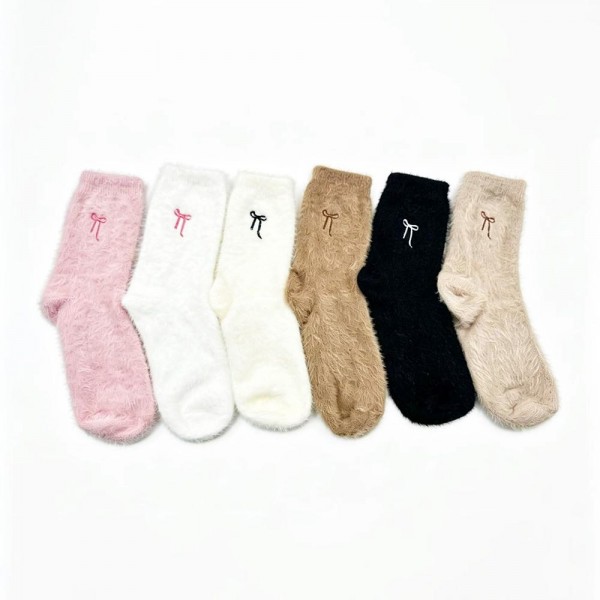 Round out your cozy assortment with this assorted six-pack of plush feather-knit crew socks finished with a tiny embroidered bow at the cuff. Knit from a brushed, fuzzy yarn blend that feels irresistibly soft against the skin, each pair adds the kind of dainty bow detail that fits perfectly into the coquette and soft-girl trend cycle — quick to photograph, quick to reorder. The mid-calf length and stretch ribbed top layer easily under jeans, leggings, and lounge sets. A boutique-perfect pick for bridesmaid gifts, hostess bundles, Valentine displays, and self-care assortments built around small luxuries.